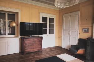 una sala de estar con TV de pantalla plana en una cómoda de madera en Maison Pistache, en Le Dorat
