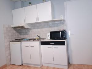 a small kitchen with white cabinets and a microwave at L'échappée Belle face aux Falaises in Le Tréport