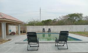 two chairs sitting in front of a swimming pool at Cozy Road Lodge in Sihangwane