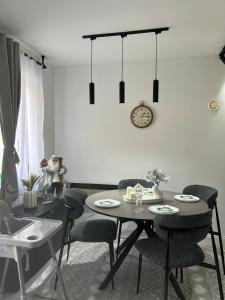 a dining room with a table and chairs and a clock at Vila Vedrana Apartman Nedeljkovic in Brzeće