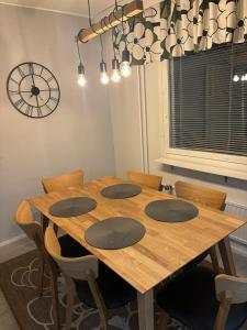 a dining room table with four chairs and a clock at Apartment for five near Railway station in Rovaniemi