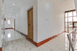 a hallway with white walls and a wooden door at Hotel O Hameed in Durgjan