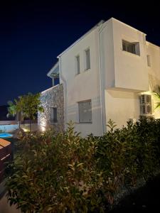a white building at night with a bush in front of it at Golden Gaia Villas in Kipía