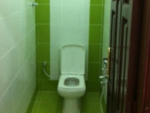 a bathroom with a toilet in a green tiled room at السعادة للشقق المفروشة in ‘Aydīd