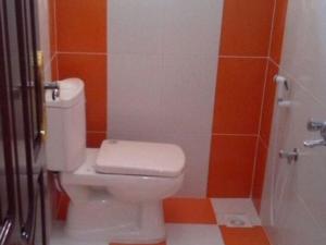 a bathroom with a white toilet and orange tiles at السعادة للشقق المفروشة in ‘Aydīd +8 photos