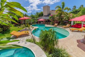 einen Pool im Garten mit Stühlen und Sonnenschirmen in der Unterkunft Xainã Pousada de Charme in Cumbuco