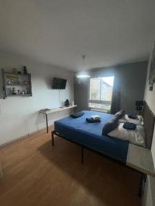 Schlafzimmer mit einem großen Bett mit blauer Bettwäsche und einem Schreibtisch in der Unterkunft Studio centre ville Les logis de Paray 321 in Paray-le-Monial