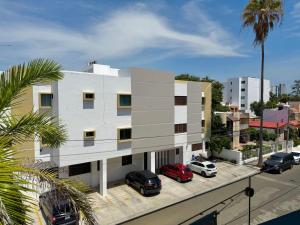 a white building with cars parked in a parking lot at Depa a unas Calles de la Playa By GPSRentas in Isla Venados