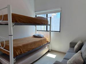 a room with two bunk beds and a couch at Depa a unas Calles de la Playa By GPSRentas in Isla Venados