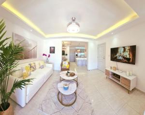 a living room with a white couch and a tv at Stylish 3BR Condo, Full AC, Wi-Fi in El Seis