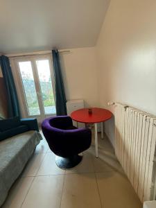 a living room with a table and a purple chair at Cristian in Livry-Gargan