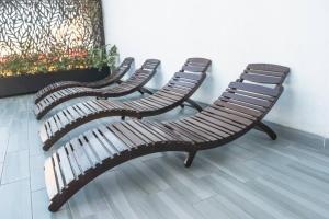 three wooden benches sitting next to a wall at Alojamiento A Unas Calles del Malecon in Mazatlán