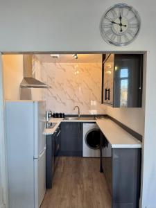 a kitchen with a refrigerator and a clock on the wall at Comfort in the East in Glasgow
