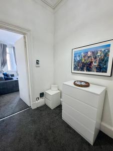 a white living room with a painting on the wall at Comfort in the East in Glasgow