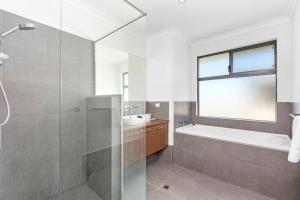 a bathroom with a shower and a tub and a sink at Coastal Retreat in Burns Beach in Kinross +35 photos
