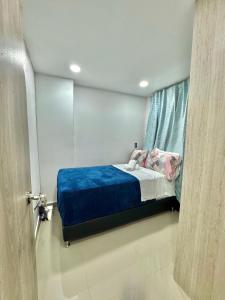 a bedroom with a bed with a blue blanket and a window at Apartamento Ideal y Tranquilo in Sabaneta