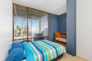 a bedroom with a crib and a large window at Sunrise By The Sea in Torquay +7 photos