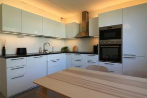 a kitchen with white cabinets and a wooden table at Central and Spacious Apartment for 4 with Sauna in Kirkkonummi