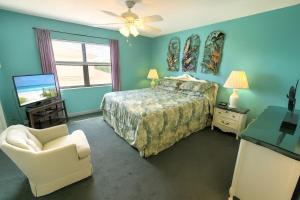 Un dormitorio con una cama y una silla y un televisor. en Oasis #18 Daytona Beach Shores Retreat-Walk To The Beach, en Daytona Beach Shores 15 fotos más