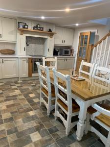 a kitchen with a wooden table and white chairs at Paul's country cottage in Donegal