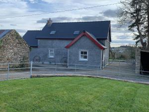 a house with a fence in front of a yard at Paul's country cottage in Donegal