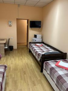 a room with two beds and a tv and a desk at Seven Hotel VIP in Korostenʼ +2 photos