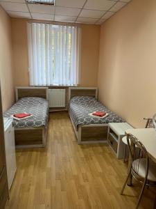 two beds in a room with a window and a table at Seven Hotel VIP in Korostenʼ