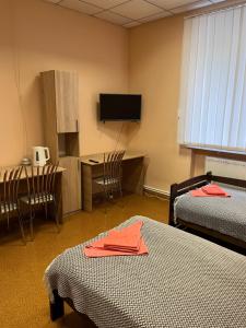a room with two beds and a desk and a television at Seven Hotel VIP in Korostenʼ