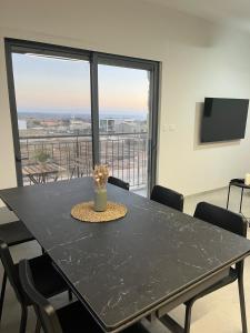 a dining room table with chairs and a large window at צימר בלב הגולן קצרין in Qasrîne