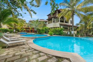 a swimming pool with palm trees in front of a building at Tropical Gardens Suites and Apartments in Coco