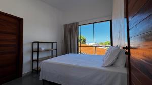 a bedroom with a bed and a large window at Chalés da Bica - Modernidade e Aconchego a 100m da Praia in Paracuru