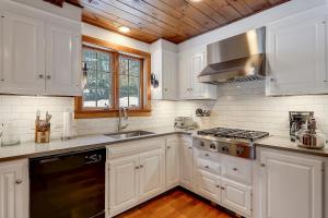 Una cocina con gabinetes blancos y un horno de estufa. en Two Chimneys: 5 br, a/c, fireplace, deck & hot tub, firepit, garage!, en Stowe 30 fotos más