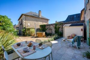 Salignac EyviguesMaison T3 tout confort et spa Le Clos des Pierres的一个带桌椅的庭院和一个车库