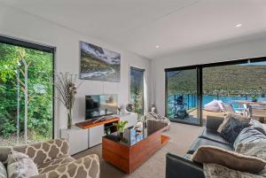 a living room with two couches and a desk and windows at Charming Lakeview Home ! in Queenstown