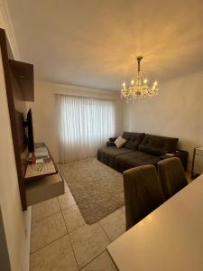 a living room with a couch and a chandelier at Vista ao mar no Gonzaga in Santos