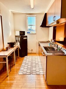 Una cocina con un fregadero y una mesa dentro. en バス停"平城札所前"徒歩0分 四国愛媛の宿 "40番たっきゅうミニホテル" "No40 Takkyu mini hotel", en Hirajō