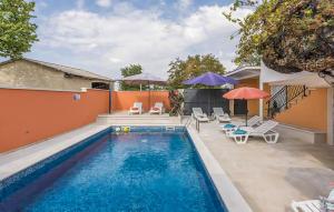 a swimming pool with chairs and umbrellas next to a house at Cozy Home In Tinjan in Tinjan +16 photos