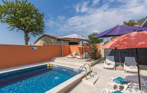 a swimming pool with umbrellas and chairs and a swimming pool at Cozy Home In Tinjan in Tinjan