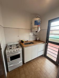 Una pequeña cocina con estufa y fregadero. en Rincon del Oceano, en Santa Teresita 2 fotos más