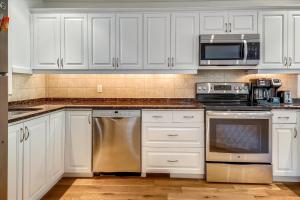 a kitchen with white cabinets and stainless steel appliances at Topnotch Retreat in Stowe