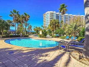 una piscina con sedie e palme e un edificio di 5 Star Resort 6th fl 2BR 2 BATH King Suite Shuttle Pools Family a Destin