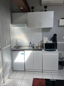 a white kitchen with a sink and a microwave at Nid Parisien in Cachan +3 photos