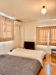 Un dormitorio con una cama y un televisor de pantalla plana. en バス停"平城札所前"徒歩0分 四国愛媛の宿 "40番たっきゅうミニホテル" "No40 Takkyu mini hotel", en Hirajō