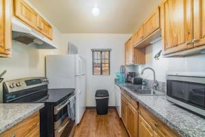 Una cocina con gabinetes de madera y un refrigerador blanco. en Mins from the UofA & Downtown 4BR 2BA Entire Home, en Tucson