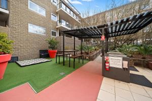 キャンベラにあるSpacious Apartment with Gym & Pool Accessの建物の前のピクニックテーブルと日よけのあるパティオ