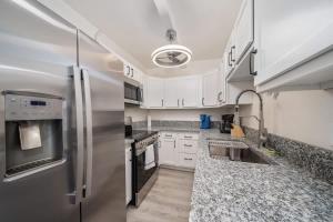 a kitchen with white cabinets and a stainless steel refrigerator at 3BR 2BA Comfy Home with Jacuzzi in Tucson