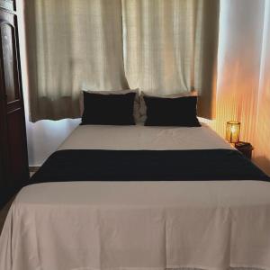 ein weißes Bett mit schwarzen Kissen im Schlafzimmer in der Unterkunft Canto da Lapa in Rio de Janeiro
