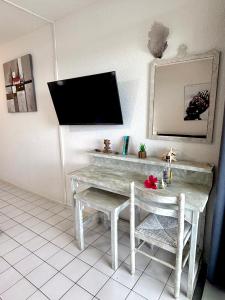 a room with a table and a tv on the wall at Le Blue Ground Vue Mer in Le Diamant