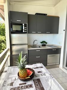 a kitchen with a bowl of fruit on a table at Le Blue Ground Vue Mer in Le Diamant