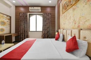 a bedroom with a large bed with red pillows at Hotel O Royal Guest House in Ludhiana